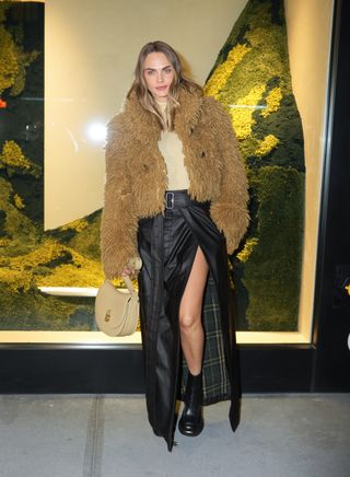 A photo of Cara Delevingne in a brown furry jacket and a black maxi skirt