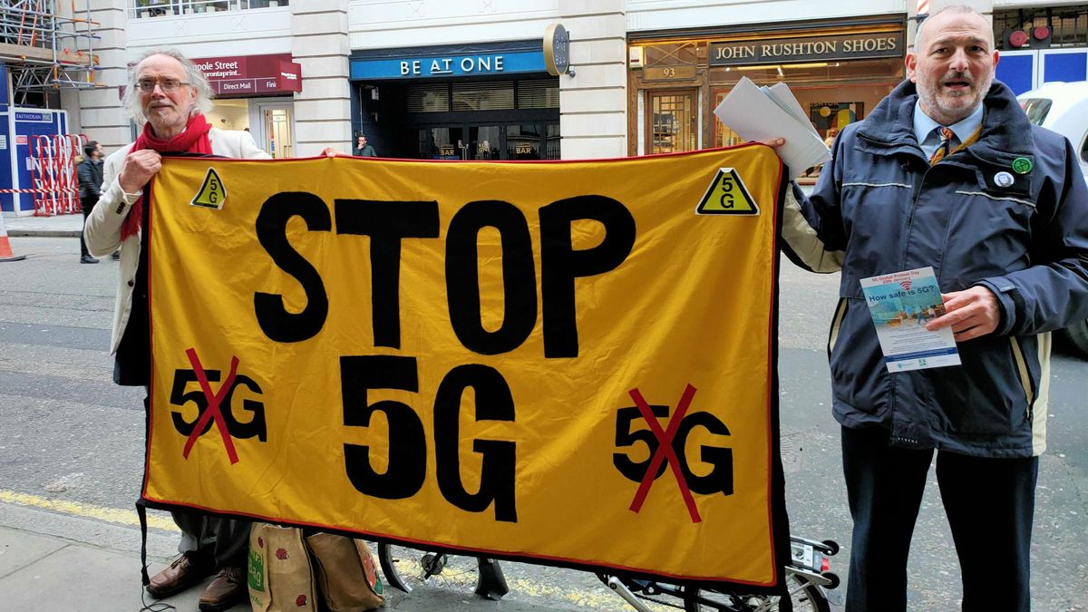 Two protesters holding a banner that says &amp;#039;Stop 5G&amp;#039;