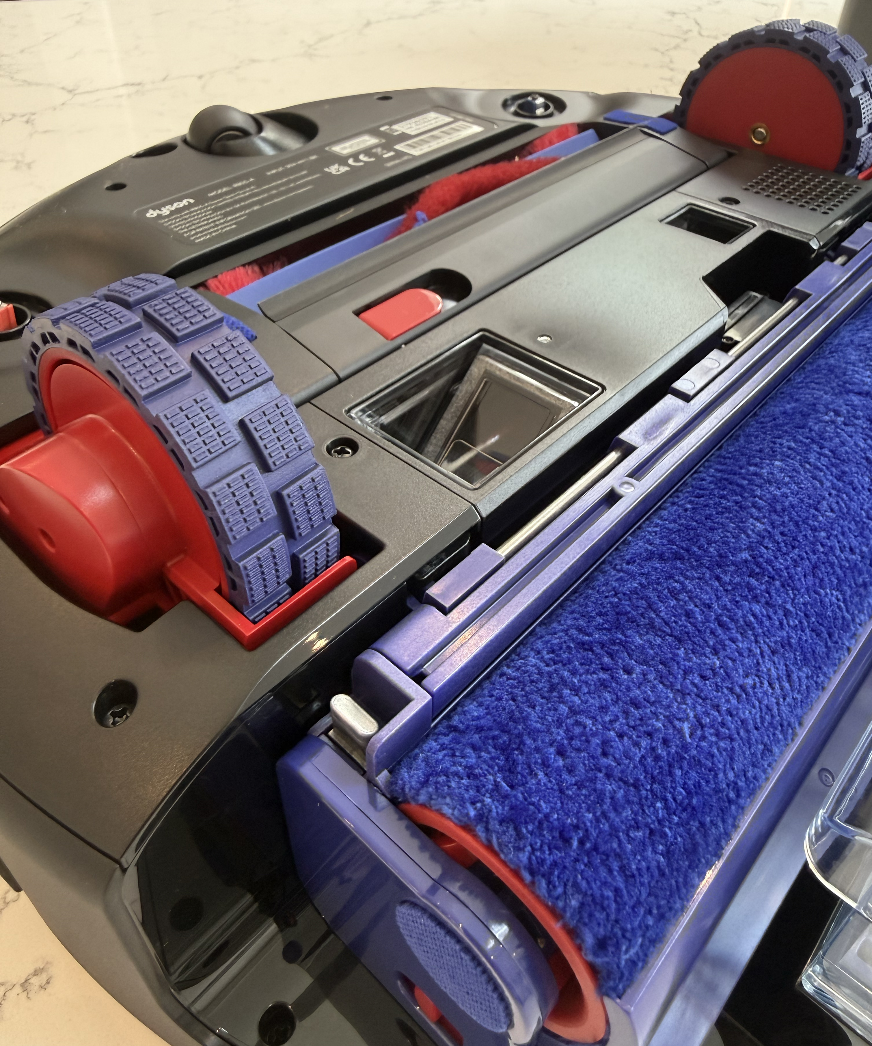 Close-up of the Dyson Spot+Scrub Ai underside showing the brush bar and blue wet roller