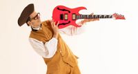 Paul Gilbert wears a tricorn and period dress as he poses in shred mode with his signature Ibanez guitar