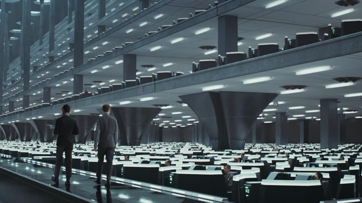 Still from the Star Wars TV show, Andor. Two men walk amongst rows and rows and rows of depressing futuristic work cubicles.