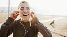 Close up of young woman's face whilst she is listening to ear buds whilst running on the beach.