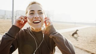Young woman listening to ear buds whilst running on the beach.