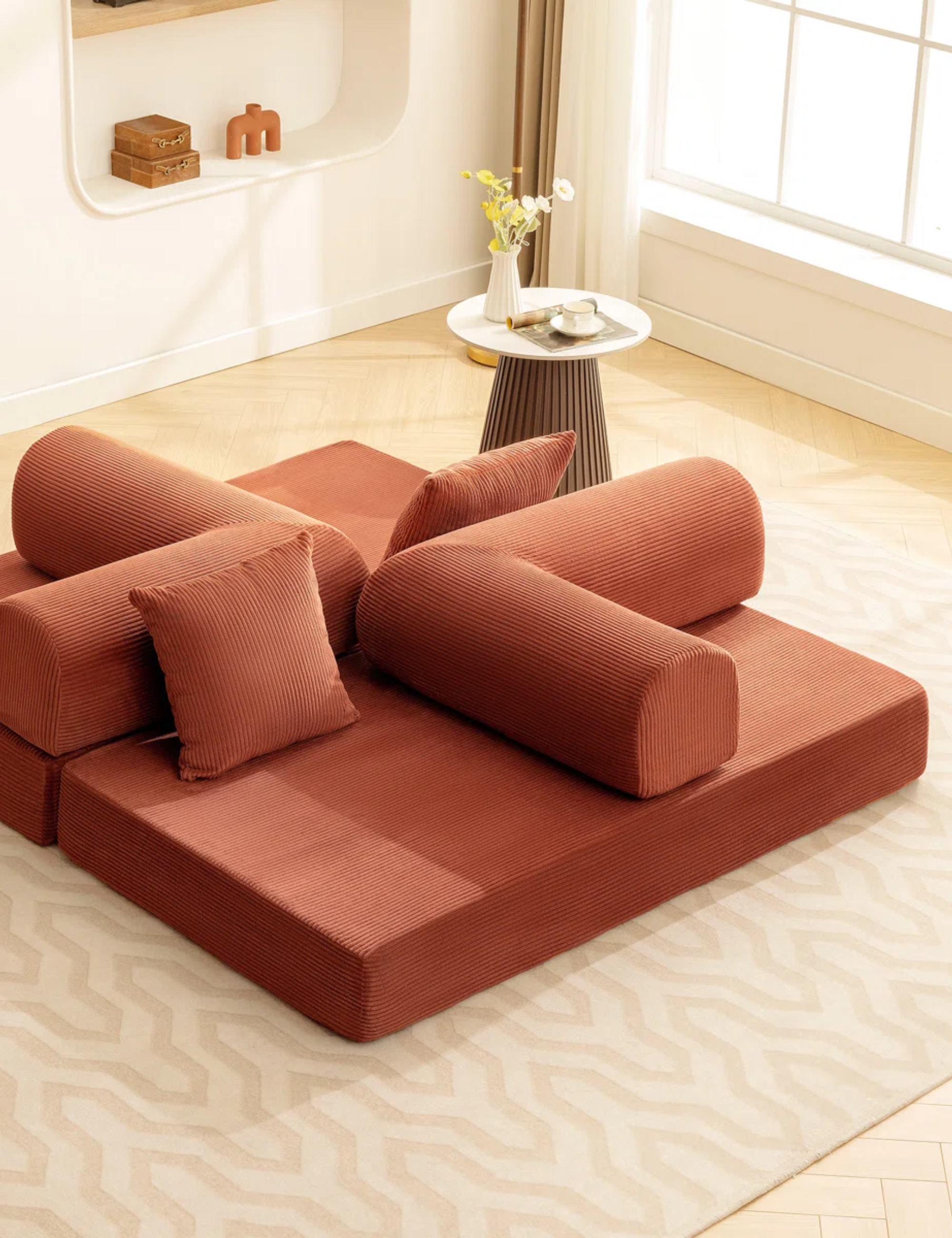 Low-slung terracotta couch arranged into four quadrants inside of a sunlit living room