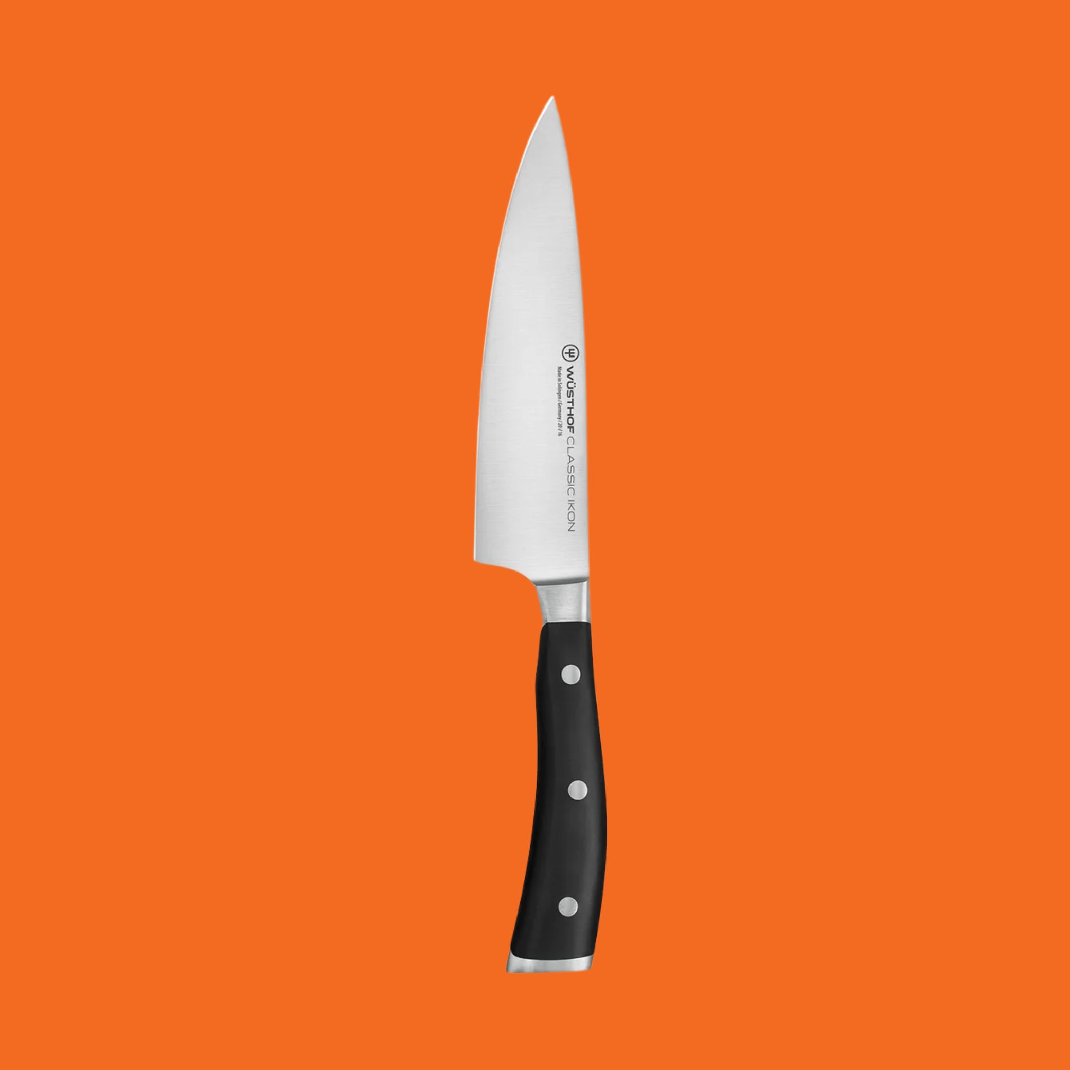 W&amp;Uuml;STHOF Classic Ikon Chef's Knife against orange background.