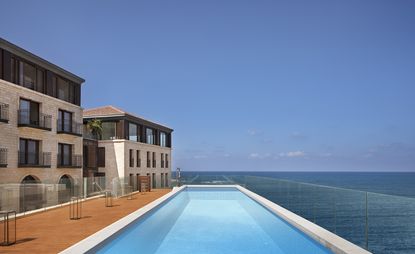 Seaside pool walled in glass railing beside the hotel