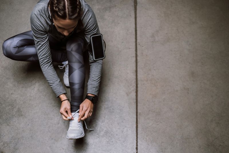 Top down view of a female runner tying her shoelaces