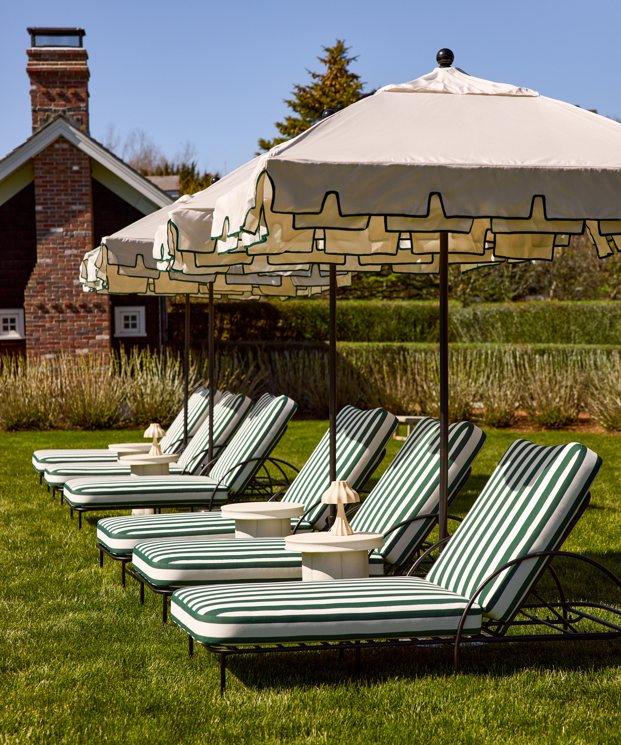 six outdoor chaise lounges in green and white stripes and a row of umbrellas