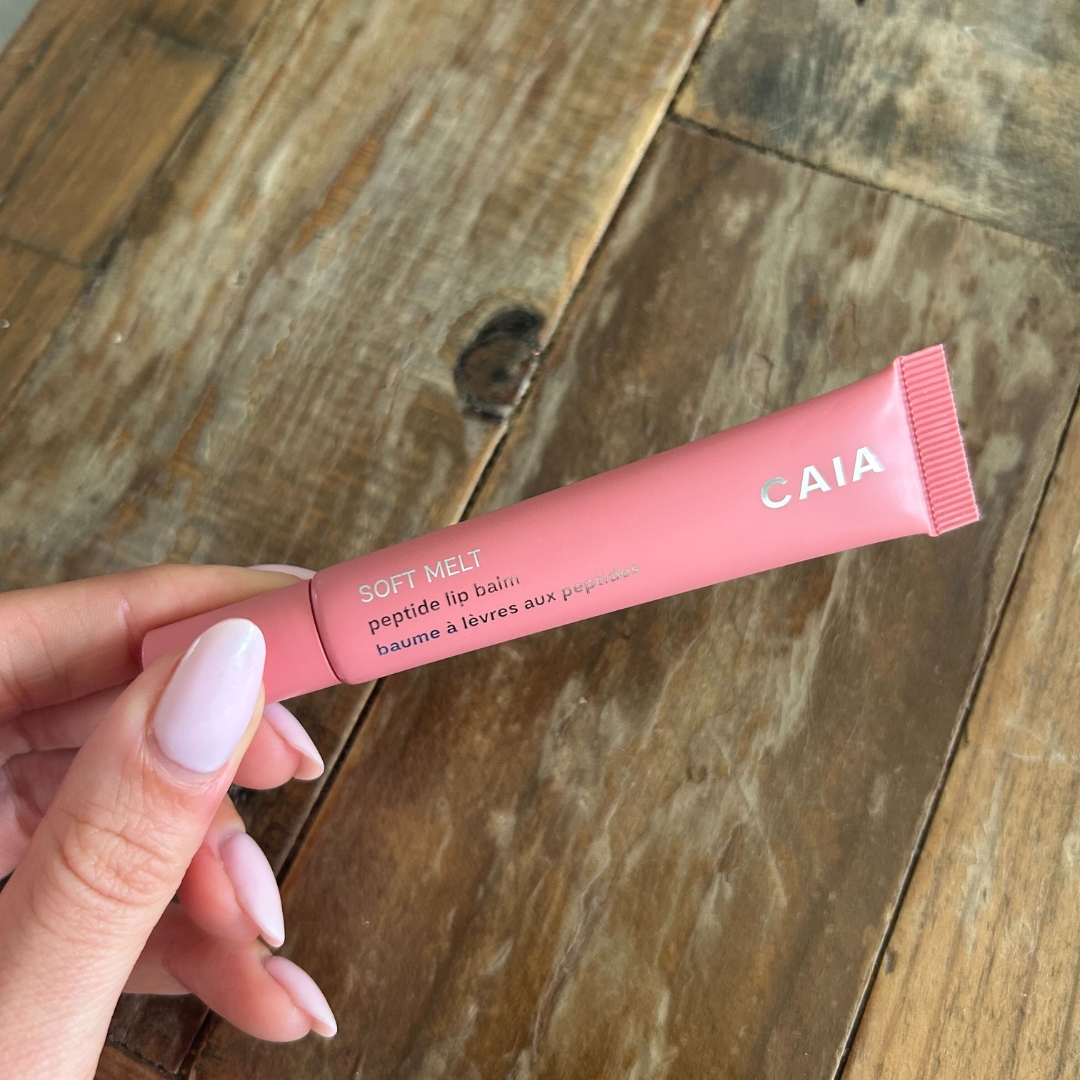 Hand holding the CAIA Soft Melt Tinted Peptide Lip Balm