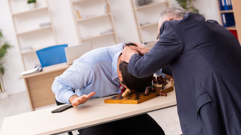 Two business men playing chess in the office.