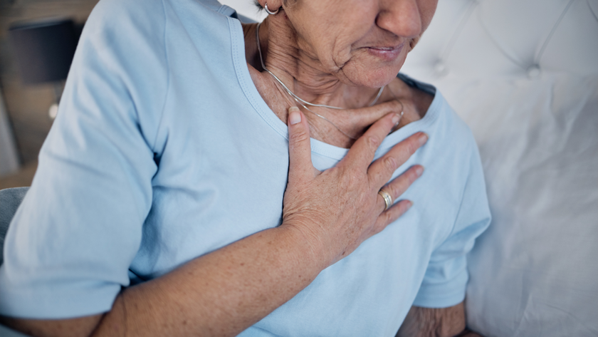 Old woman in bed and chest pain in the morning, discomfort and emergency for illness. Medical, mature female and elderly lady in bedroom, heart attack and panic attack with hand touching body.