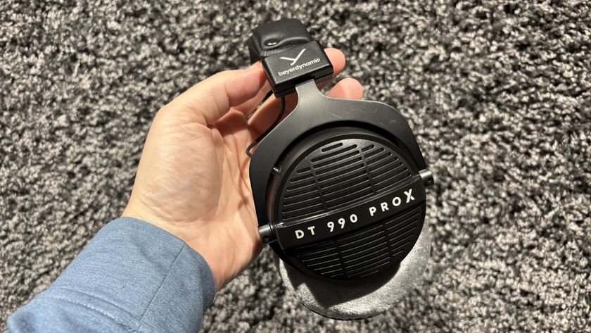 Beyerdynamic DT 990 Pro X headphones in black being held against a grey carpet