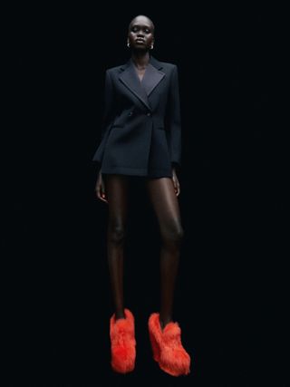 Woman in black suit and furry orange shoes
