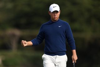 Tom Kim fist pumps after holing a putt