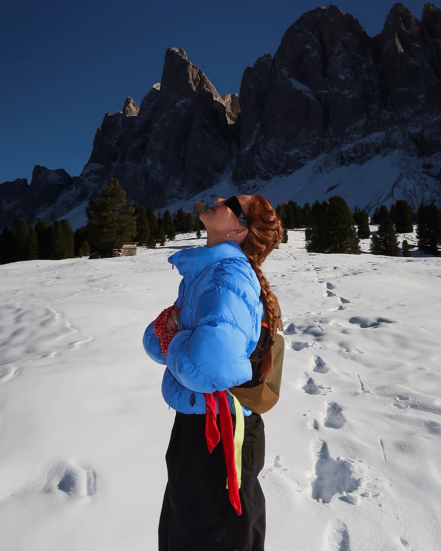 A woman in the mountains wearing a blue puffer coat with a braided ponytail hairstyle