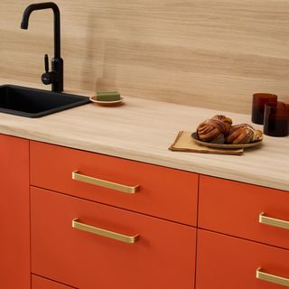 Plank Hardware red kitchen with brass handles.