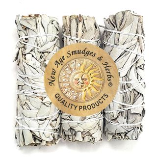 Three bundles of sage tied with white string with a large orange circular logo with black text and sun motif