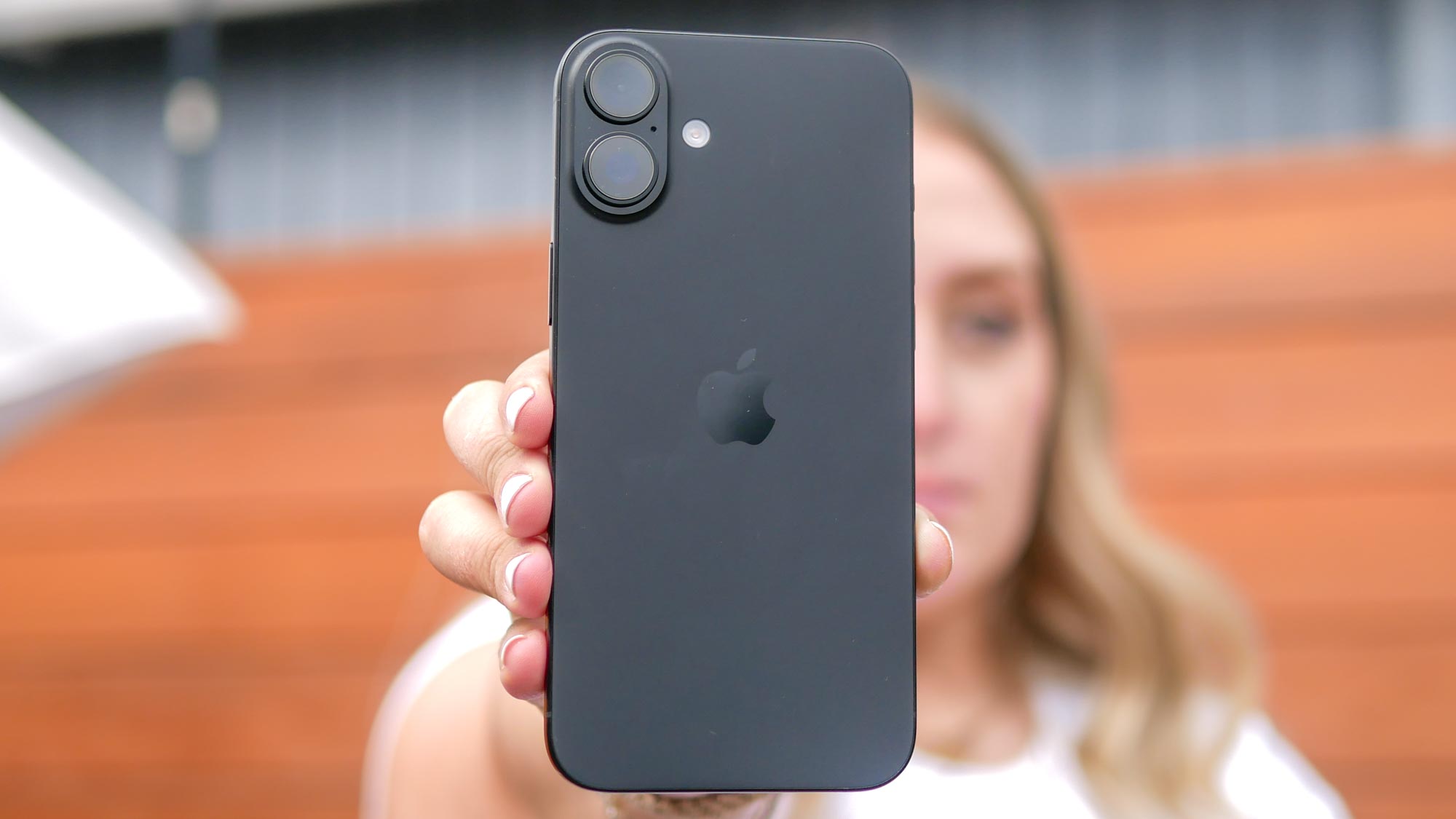 Person holding the Apple iPhone 16 Plus to reveal the rear side of the phone and camera array
