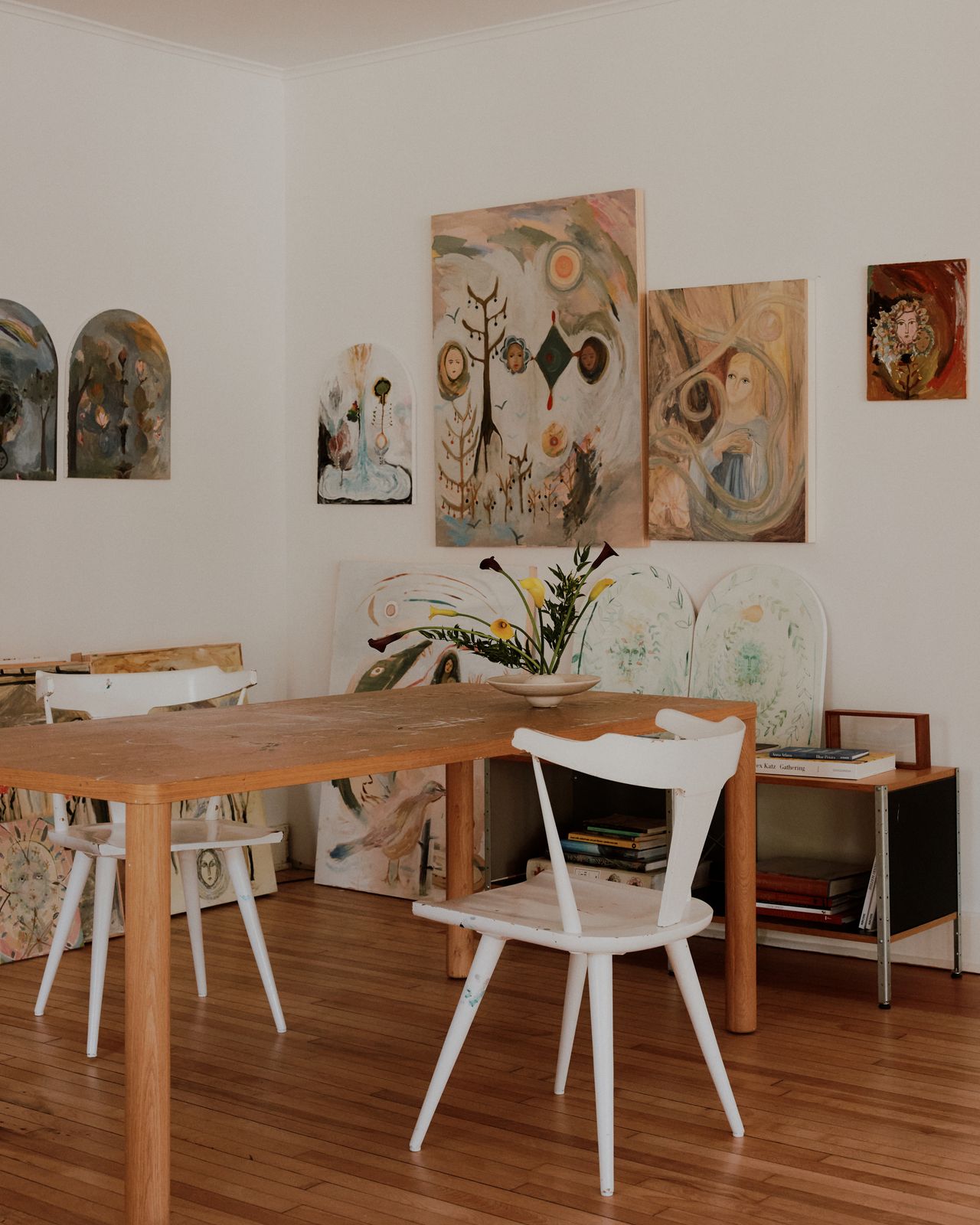 A pair of white chairs at a table with art on the walls at Rachel Cope's art studio in upstate New York