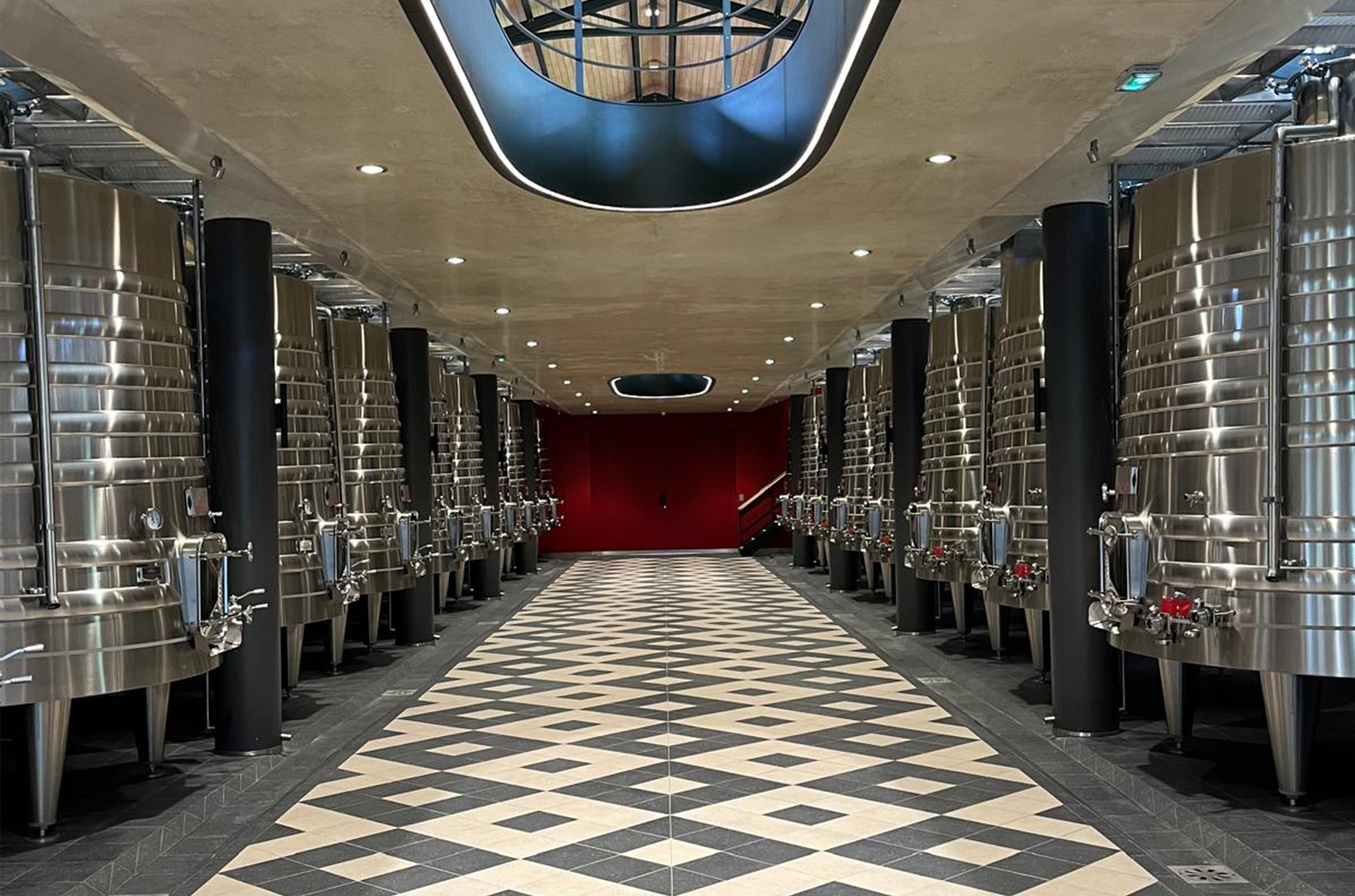 Room with six large stainless steel tanks on each side, and tiled flooring