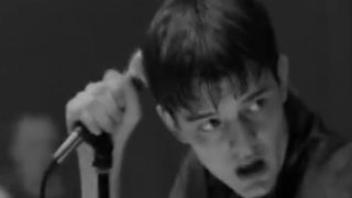 Sam Riley holding a microphone as Ian Curtis in Control