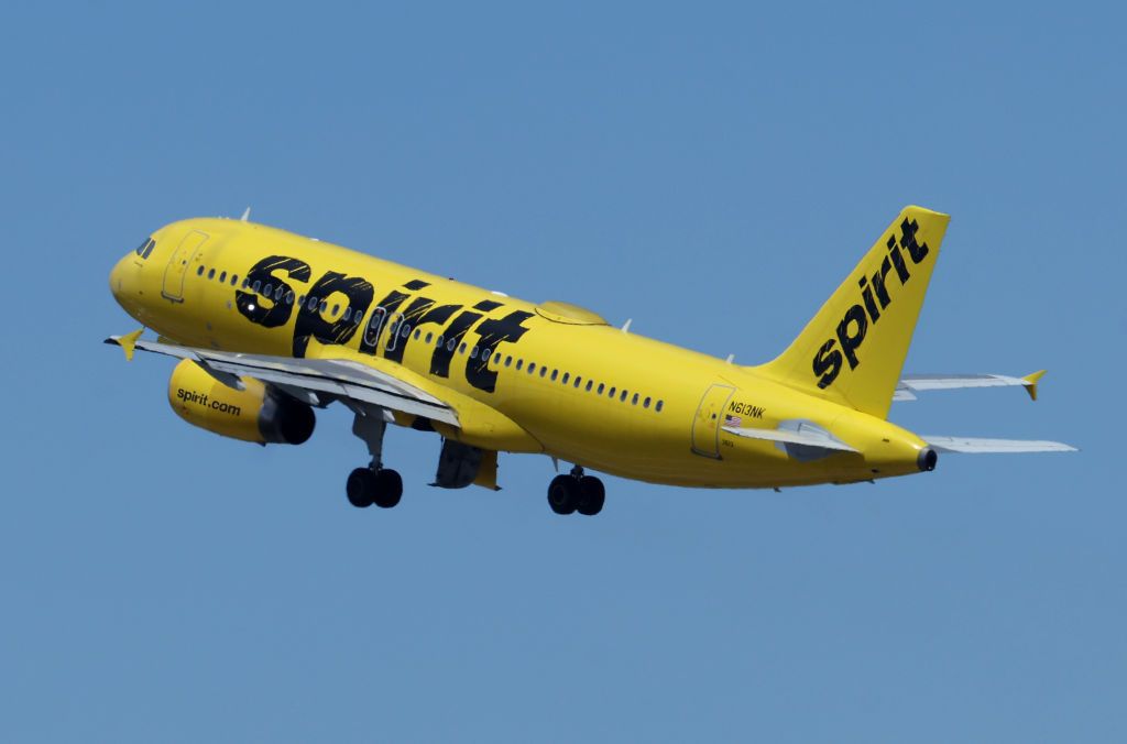 A yellow Spirit Airlines airplane flying in blue skies