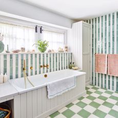 bathroom with bathtub, window shelf, green and white chequered floor tiles and stripey wall tiles