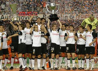 Valencia celebrate with the two cups after winning the Spanish soccer league 2004 title and the UEFA cup Valencia 23 May 2004. (Photo credit should read JOSE JORDAN/AFP via Getty Images)