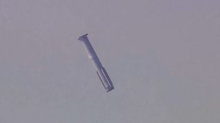a silver-gray rocket is seen in a gray sky
