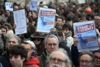 People holding up signs that say "Stand up for Science" at a protest.