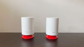TP-Link Deco Voice X20 system on a dark wood table next to a white wall