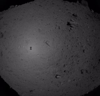 Japan's Hayabusa2 spacecraft captured this photo during its sample-grabbing descent toward the asteroid Ryugu on Feb. 21, 2019. The probe's shadow is visible on the space rock's surface.