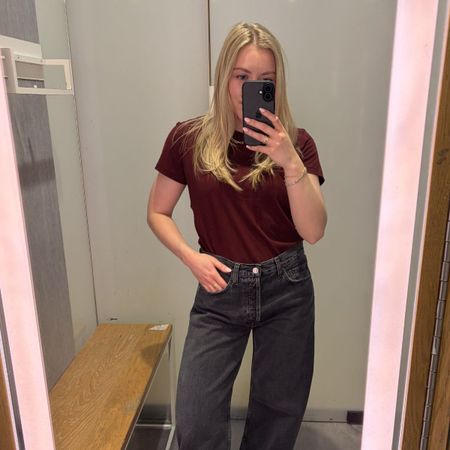 Woman wears burgundy T-shirt, grey jeans
