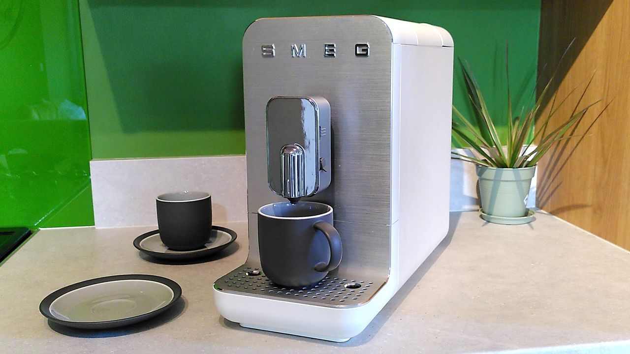 Smeg BCC13 coffee maker with cups and house plant on kitchen counter