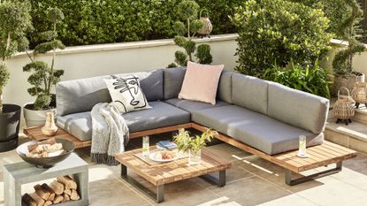 Garden living area designed using garden trends with a grey corner sofa and low wooden coffee table