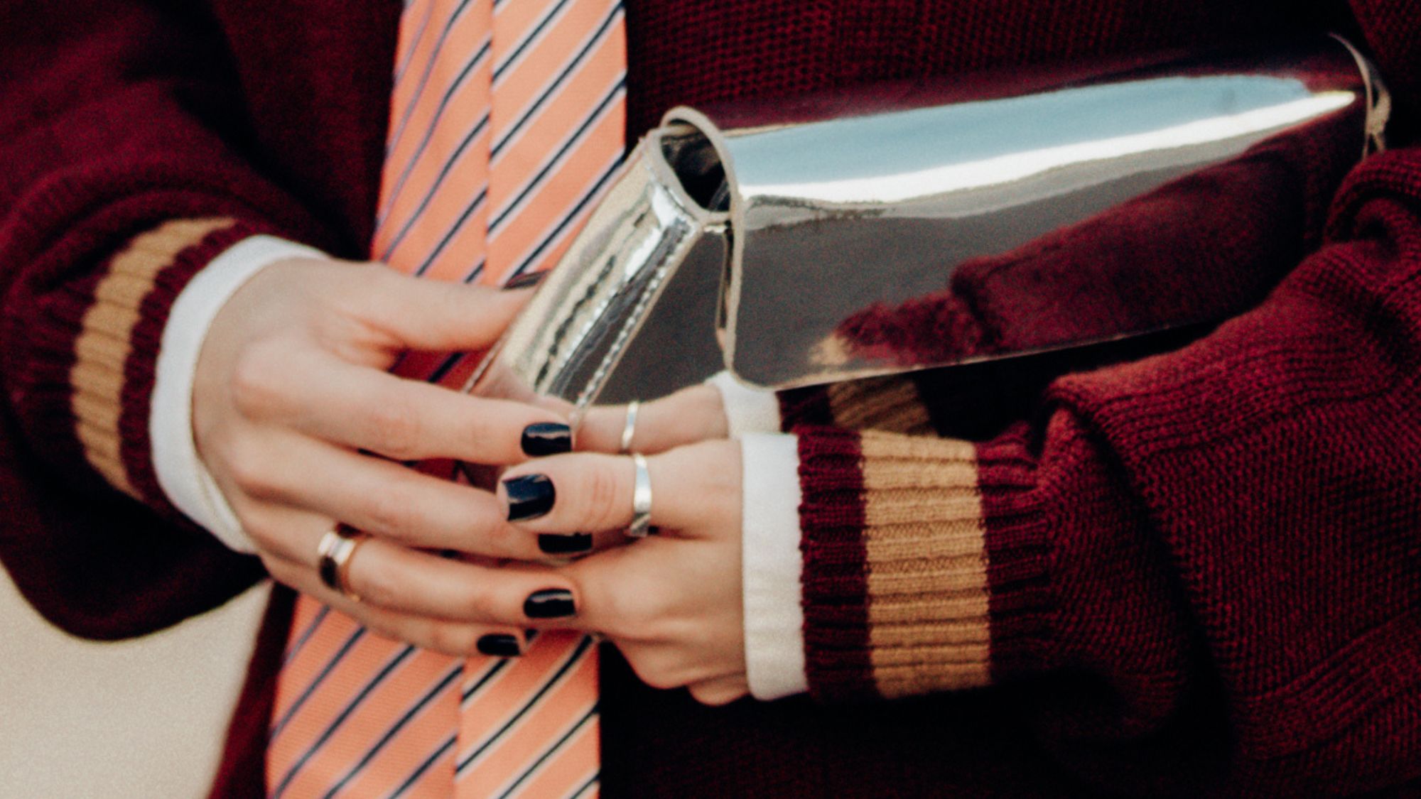 close up of woman at fashion week holding a silver bag with her dark nails on show