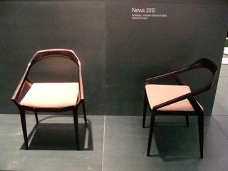 Two brown chairs photographed on a grey floor against a grey wall