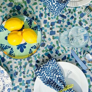 Blue table cloth with bowl of lemons and plates