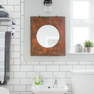 bathroom with embossed copper mirror on wall and white window