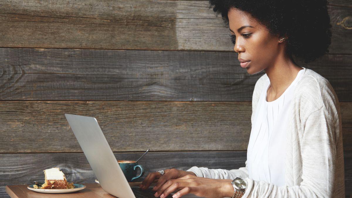 Woman working on laptop in a cafe with coffee and cake