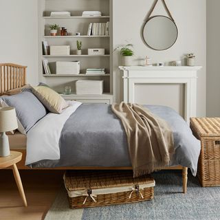 grey bedroom with wooden bed and wicker underbed chest