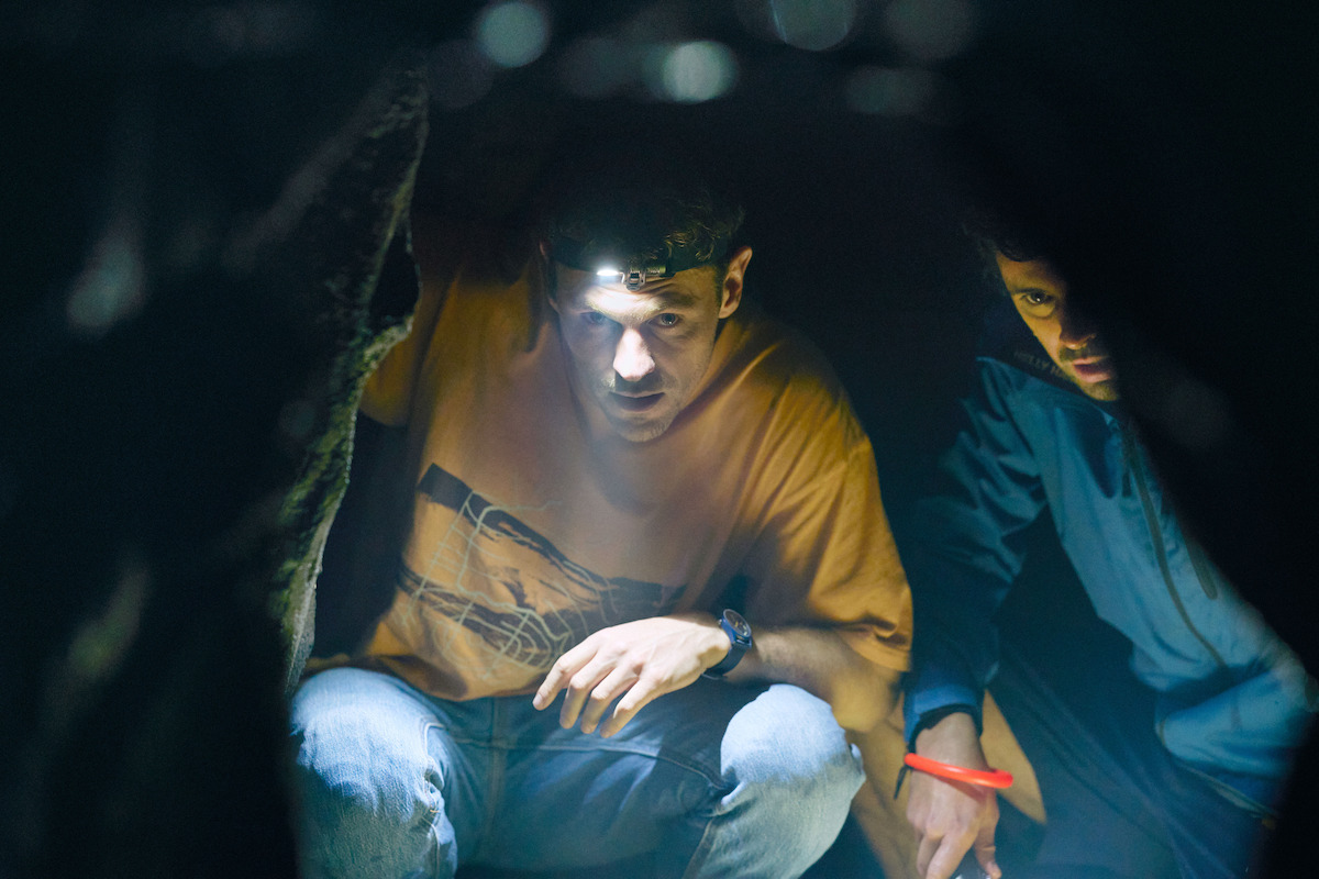 charlie vickers and thom green peer into a cave in a still from the survivors