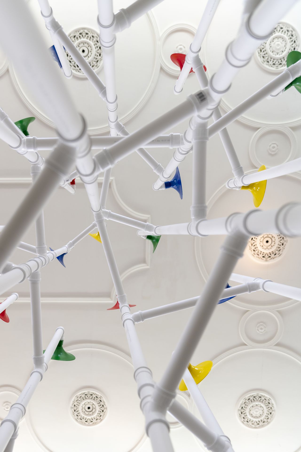 Installation in a former church made out of white pipes and colourful funnels
