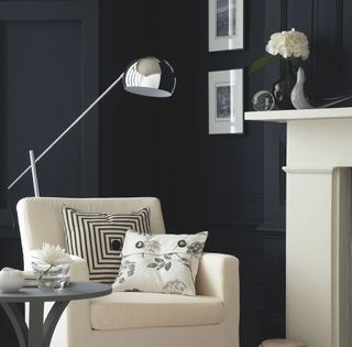 living area with black wall and white armchair and fireplace