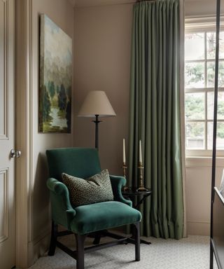 corner of bedroom with beige walls, green armchair and green curtains