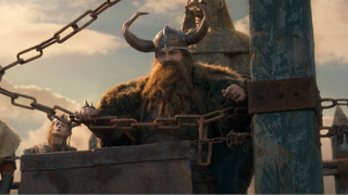 Gerard Butler as Stoick standing on a ledge with cains in front of him in the live-action How To Train Your Dragon. 