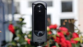 Ricoh Theta X 360 cameras with a blurred background with red flowers