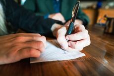 Close-up of a woman's hands writing on napkin at coffee shop