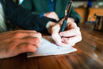 Close-up of a woman's hands writing on napkin at coffee shop