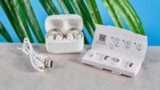 Soundcore AeroClip open-ear earbuds in champagne mist against a blue backdrop